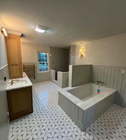 Bathroom renovation (before and after) finished view with new patterned tile floor, tub surround, and updated lighting